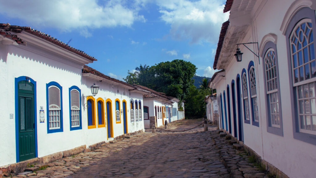 Rua de pedra no Centro Histórico de Paraty, com casas coloniais de fachada branca e portas coloridas.