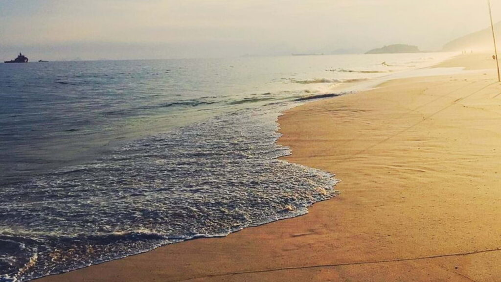 Praia de Piratininga em Niterói, com faixa larga de areia e mar com ondas.