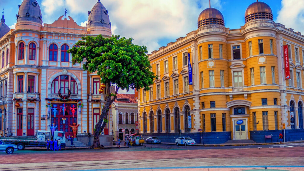 Vista do Marco Zero no Recife Antigo, com as construções históricas e o calçadão colorido ao redor.