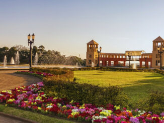 Parque Tanguá em Curitiba, com torres, jardins floridos e fontes ao entardecer, cartão-postal da capital paranaense.