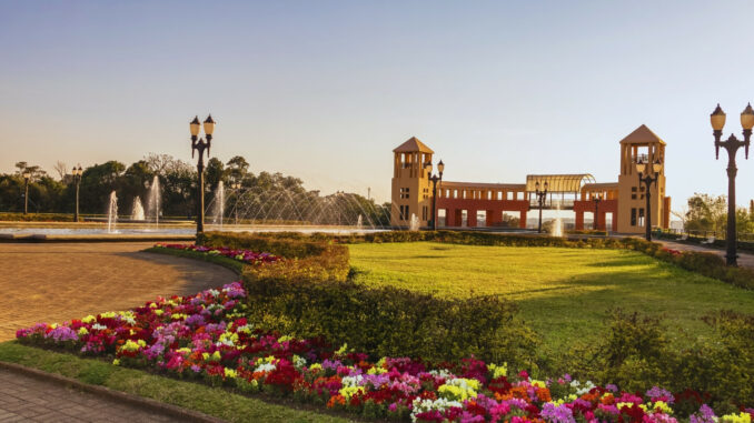 Parque Tanguá em Curitiba, com torres, jardins floridos e fontes ao entardecer, cartão-postal da capital paranaense.