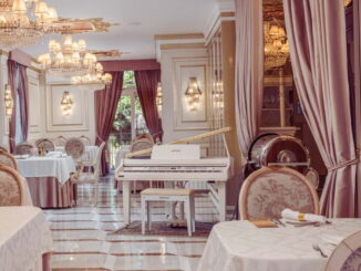 Salão do restaurante do Colline de France em Gramado com piano branco e lustres de cristal.