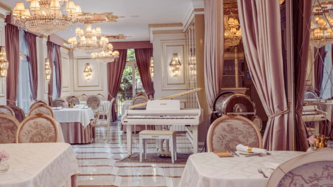 Salão do restaurante do Colline de France em Gramado com piano branco e lustres de cristal.