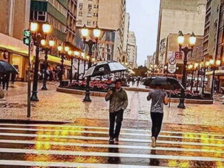 Pedestres com guarda-chuvas caminhando no centro de Curitiba em um mês chuvoso.