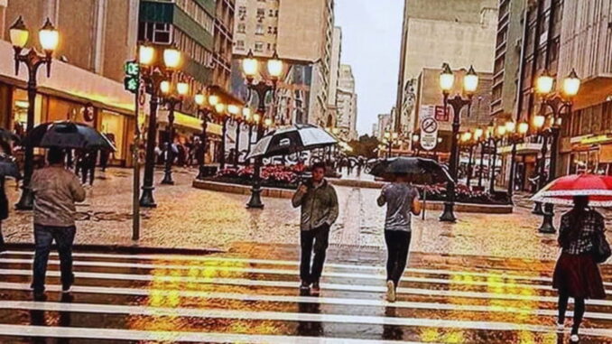 Pedestres com guarda-chuvas caminhando no centro de Curitiba em um mês chuvoso.