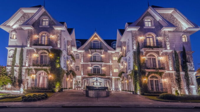 Fachada iluminada do hotel Colline de France em Gramado durante a noite.