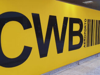 Painel amarelo com as letras CWB em destaque na área interna do Aeroporto Internacional Afonso Pena, em Curitiba.